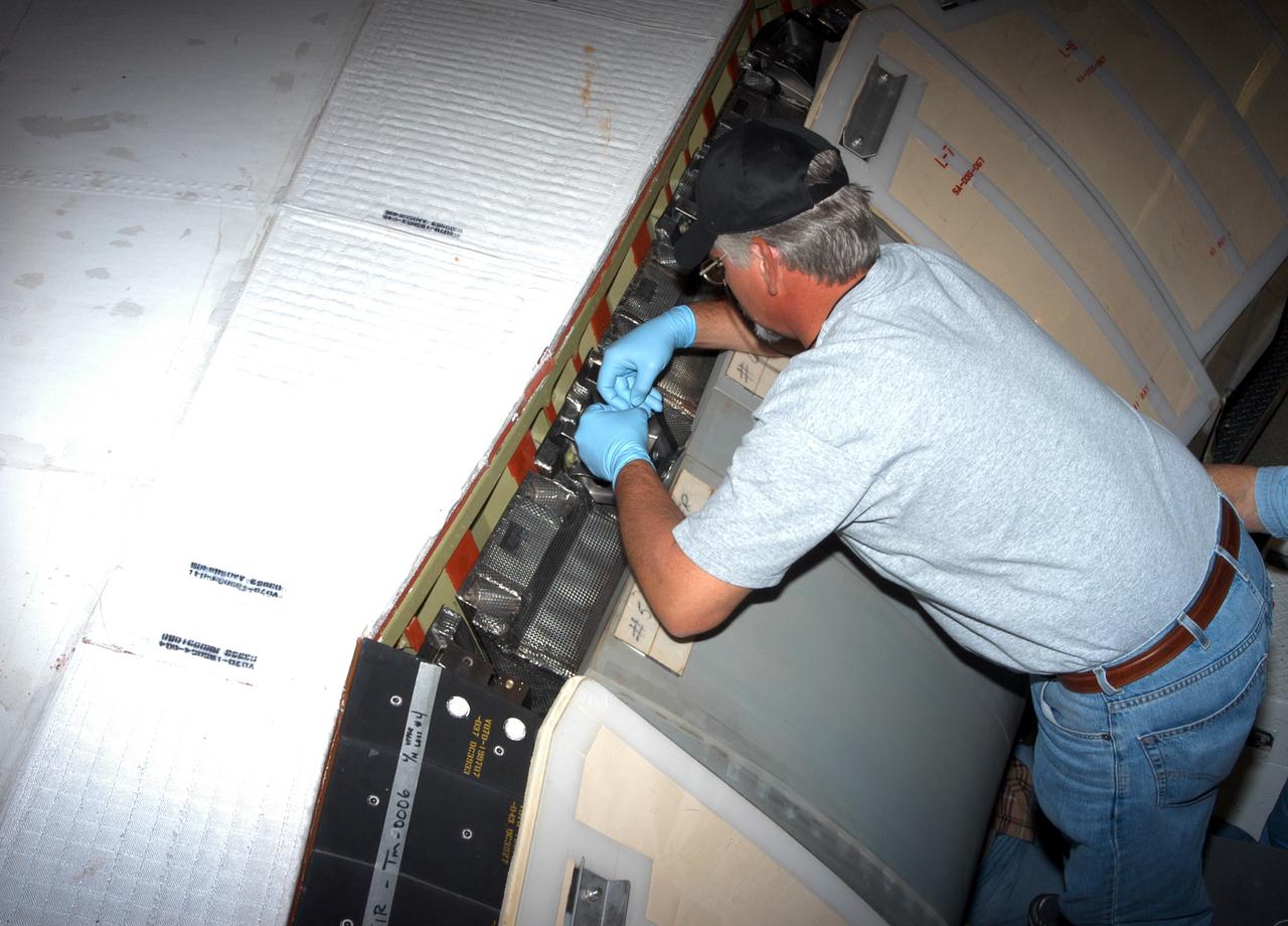 KENNEDY SPACE CENTER, FLA. - In the Orbiter Processing Facility, workers install C-shaped T-seals, which fit between each Reinforced Carbon Carbon panel, on the left-side wing leading edge of the orbiter Atlantis.