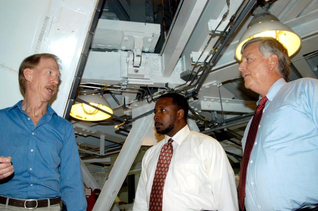 NASA image: KENNEDY SPACE CENTER, FLA. - On a tour of the Orbiter Processing Facility, Center Director Jim Kennedy (right) and Deputy Director Woodrow Whitlow Jr. (center) talk to Tom Roberts, who is with United Space Alliance, about work being done on the orbiter Endeavour.  The vehicle is in its Orbiter Major Modification period, which began in December 2003.