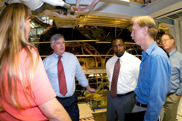 NASA image: KENNEDY SPACE CENTER, FLA. - On a tour of the Orbiter Processing Facility, Center Director Jim Kennedy and Deputy Director Woodrow Whitlow Jr.  (center, left and right) talk with Kathy Laufenberg, Orbiter Airframe Engineering ground area manager,  and Tom Roberts, Airframe Enginering System specialist, both with United Space Alliance. At far right is Bruce Buckingham, assistant to Dr. Whitlow.  They are standing in front of the aft base heatshield of Endeavour, which is in its Orbiter Major Modification period that began in December 2003.