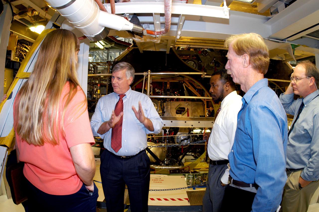 KENNEDY SPACE CENTER, FLA. - On a tour of the Orbiter Processing Facility, Center Director Jim Kennedy and Deputy Director Woodrow Whitlow Jr.  (center, left and right) talk with Kathy Laufenberg, Orbiter Airframe Engineering ground rea manager,  and Tom Roberts, Airframe Engineering System specialist, both with United Space Alliance. At far right is Bruce Buckingham, assistant to Dr. Whitlow.  They are standing in front of the aft base heatshield of Endeavour, which is in its Orbiter Major Modification period that began in December 2003.