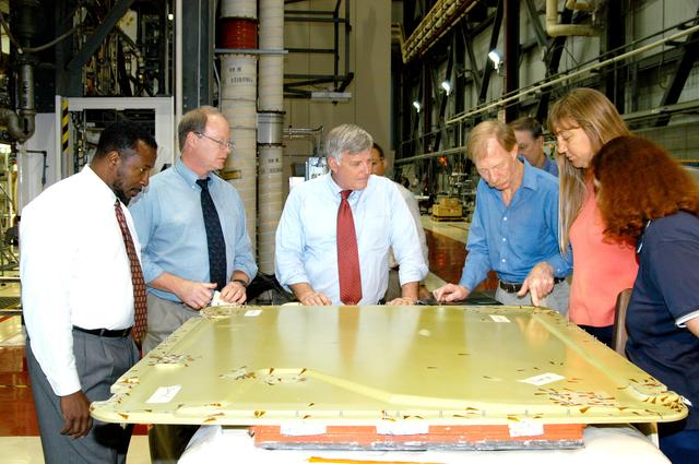 NASA image: KENNEDY SPACE CENTER, FLA. - On a tour of the Orbiter Processing Facility, Center Director Jim Kennedy (center) and Deputy Director Woodrow Whitlow Jr. (far left) look at the external tank door corrosion work being done on Endeavour.  Next to Whitlow is Bruce Buckingham, assistant to the deputy director.  Providing information, at right, are Kathy Laufenberg, Orbiter Airframe Engineering ground area manager, and Tom Roberts, Airframe Engineering System specialist, both with United Space Alliance; and Joy Huff, with Space Shuttle Processing.  Endeavour is in its Orbiter Major Modification period, which began in December 2003.