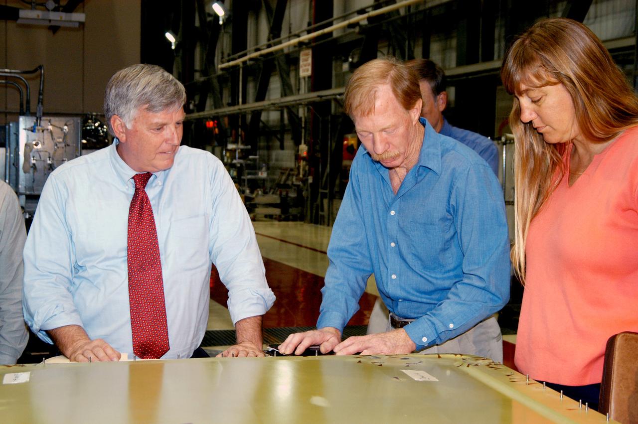 KENNEDY SPACE CENTER, FLA. - On a tour of the Orbiter Processing Facility, Center Director Jim Kennedy (left) looks at an external tank door corrosion work being done on Endeavour.  At right, Tom Roberts, Airframe Engineering System specialist with United Space Alliance, is describing the work. At right is Kathy Laufenberg, Orbiter Airframe Engineering ground area manager,also with USA.  Endeavour is in its Orbiter Major Modification period, which began in December 2003.
