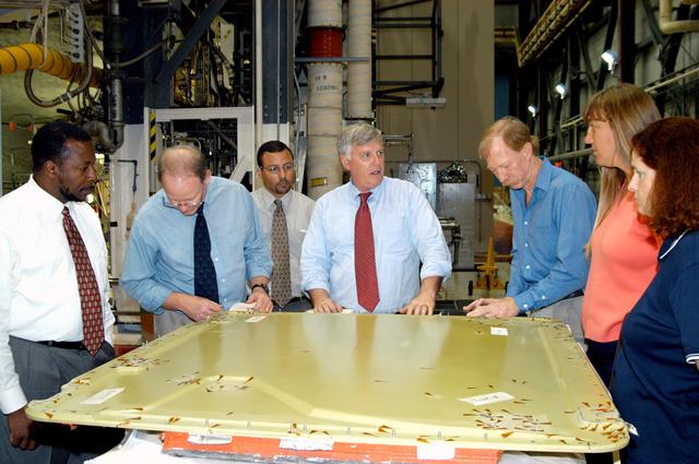NASA image: KENNEDY SPACE CENTER, FLA. - On a tour of the Orbiter Processing Facility, Center Director Jim Kennedy (center) and Deputy Director Woodrow Whitlow Jr. (far left) look at the external tank door corrosion work being done on Endeavour.  Next to Whitlow is Bruce Buckingham, assistant to the deputy director.  Providing information, at right, are Orbiter Airframe Engineering ground area manager, and Tom Roberts, Airframe Engineering System specialist, both with United Space Alliance; and Joy Huff, with KSC Space Shuttle Processing.  Endeavour is in its Orbiter Major Modification period, which began in December 2003.
