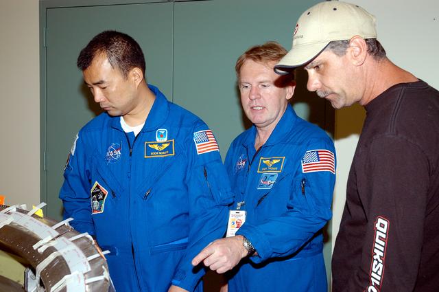 NASA image: KENNEDY SPACE CENTER, FLA. -  Members of the STS-114 crew spend time becoming familiar with Shuttle and mission equipment.  Mission Specialists Soichi Noguchi (left) and Andrew Thomas (center) look at an engine eyelet, which serves as part of the thermal protection system on an orbiter.  Noguchi is with the Japanese Aerospace Exploration Agency (JAXA).  The mission is Logistics Flight 1, which is scheduled to deliver supplies and equipment and the external stowage platform to the International Space Station.