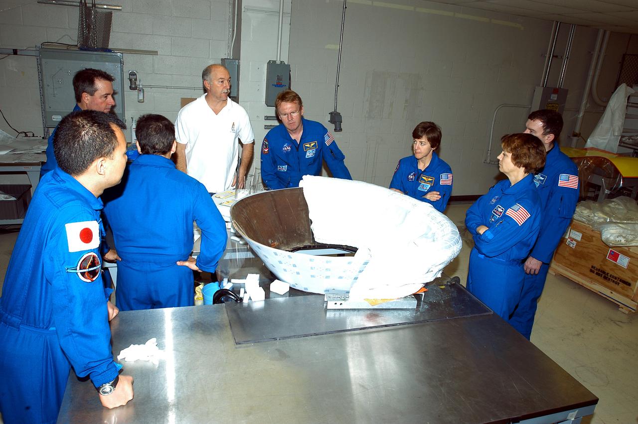 KENNEDY SPACE CENTER, FLA. - Members of the STS-114 crew spend time becoming familiar with Shuttle and mission equipment. From left (in their blue suits) are Mission Specialists Soichi Noguchi, Stephen Robinson, Charles Camarda, Andrew Thomas and Wendy Lawrence; Commander Eileen Collins and Pilot James Kelly. Noguchi represents the Japanese Aerospace and Exploration Agency.   They are looking at the thermal protection system insulation blankets being installed on an insert for Discovery’s nose cap. The STS-114 mission is Logistics Flight 1, which is scheduled to deliver supplies and equipment plus the external stowage platform to the International Space Station.