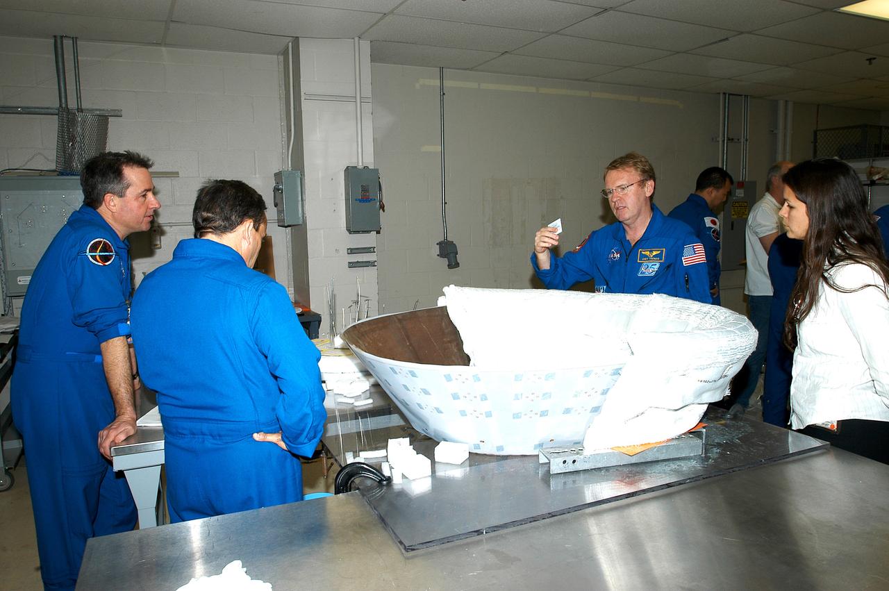 KENNEDY SPACE CENTER, FLA. - Members of the STS-114 crew spend time becoming familiar with Shuttle and mission equipment.  From left are Mission Specialists Stephen Robinson, Charles Camarda and Andrew Thomas.  On the work stand is the insert for Discovery’s nose cap, which is being fitted with themal protection system insulation blankets.  The mission is Logistics Flight 1, which is scheduled to deliver supplies and equipment plus the external stowage platform to the International Space Station.