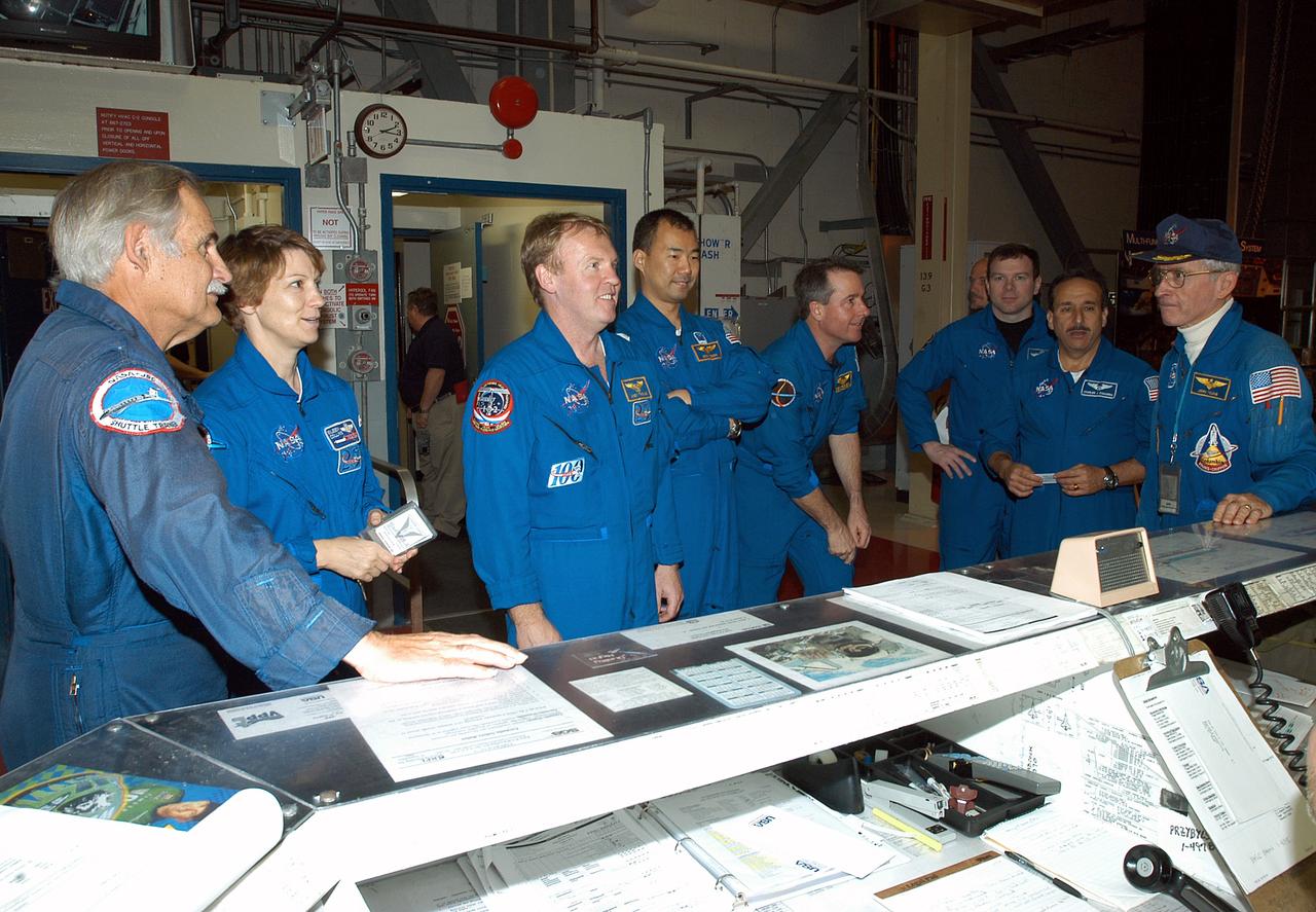 KENNEDY SPACE CENTER, FLA. - The STS-114 crew stands in front of the operations desk in the Orbiter Processing Facility.  At far right is astronaut John Young, who flew on the first flight of Space Shuttle Columbia with Robert Crippen. Young is associate director, Technical, at Johnson Space Center.  From left are Young’s pilot; STS-114 Commander Eileen Collins; Mission Specialists Andrew Thomas, Soichi Noguchi and Stephen Robinson; Pilot James Kelly; and Mission Specialist Charles Camarda. Noguchi represents the Japanese Aerospace and Exploration Agency.  The STS-114 crew is spending time becoming familiar with Shuttle and mission equipment.  The mission is Logistics Flight 1, which is scheduled to deliver supplies and equipment plus the external stowage platform to the International Space Station.