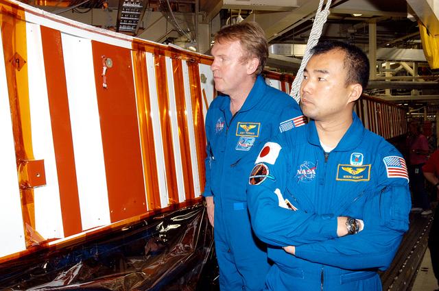 NASA image: KENNEDY SPACE CENTER, FLA. - STS-114 Mission Specialists Andrew Thomas and Soichi Noguchi look at the leading edge of Discovery’s wing with RCC panels removed. Noguchi is with the Japanese Aerospace and Exploration Agency.   Crew members are at KSC becoming familiar with Shuttle and mission equipment. The mission is Logistics Flight 1, which is scheduled to deliver supplies and equipment plus the external stowage platform to the International Space Station.