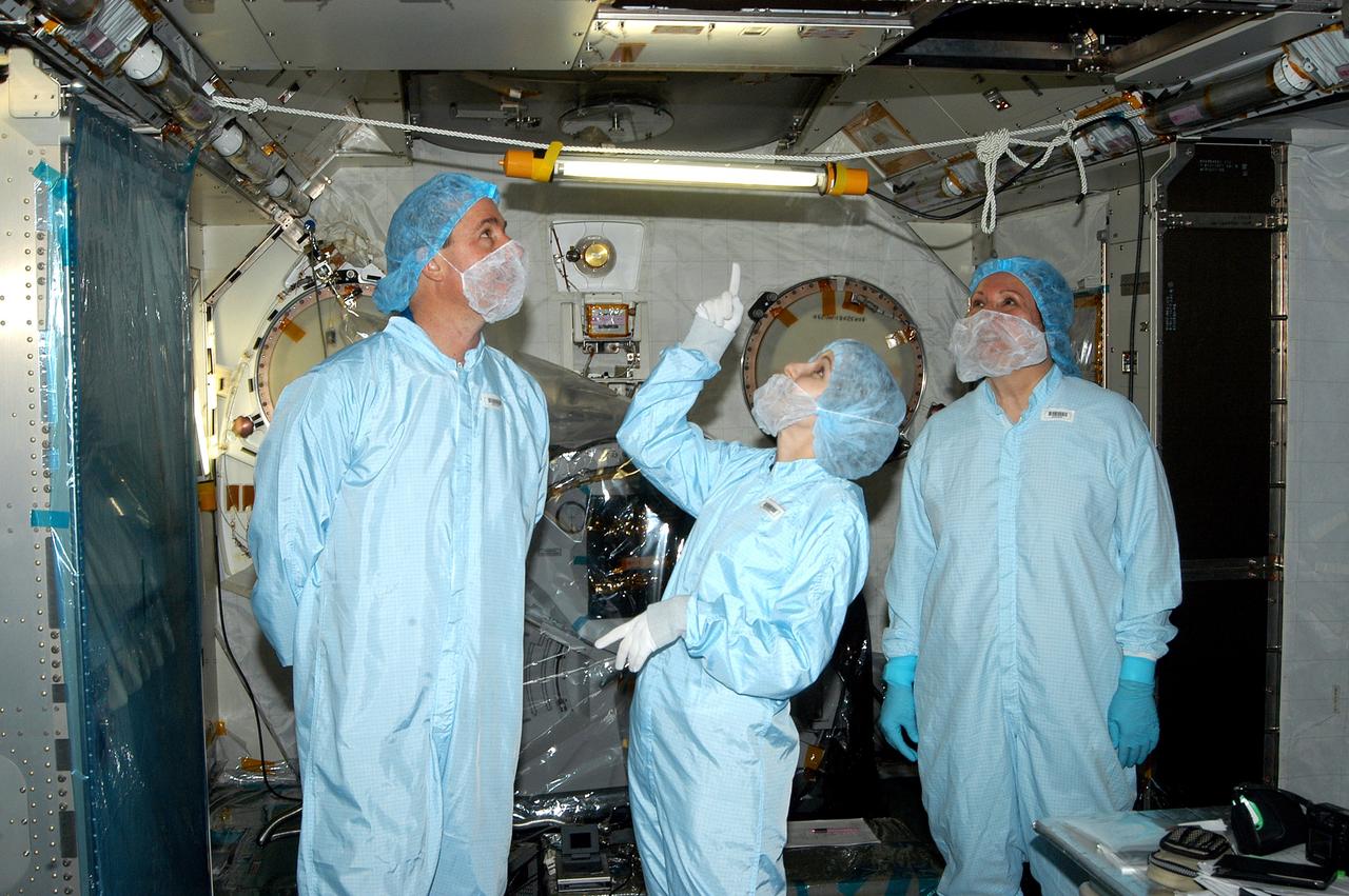 KENNEDY SPACE CENTER, FLA. - In the Space Station Processing Facility, STS-114 Mission Specialist Stephen Robinson (left) looks at an area overhead in the Japanese Experiment Module (JEM). In the center is Jennifer Goldsmith, with United Space Alliance at Johnson Space Center, and at right is Louise Kleba, with USA at KSC.  Crew members are at KSC becoming familiar with Shuttle and mission equipment. The mission is Logistics Flight 1, which is scheduled to deliver supplies and equipment plus the external stowage platform to the International Space Station.