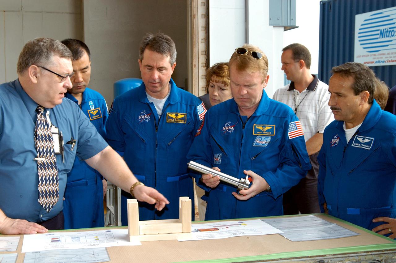 KENNEDY SPACE CENTER, FLA. -  -  In the SRB Assembly and Refurbishment Facility, some of the STS-114 crew listen to Mike Leppert, Manufacturing Operations project lead with United Space Alliance, talk about a booster separation motor (BSM) igniter.  Pictures on the table give expanded views of the BSM and igniter.  Next to Leppart, from left, are Mission Specialists Soichi Noguchi and Stephen Robinson; Commander Eileen Collins; and Mission Specialists Andrew Thomas (holding a mockup of an igniter) and Charles Camarda.  Noguchi is with the Japanese Aerospace and Exploration Agency.  The crew is at KSC for familiarization with Shuttle and mission equipment. The STS-114 mission is Logistics Flight 1, which is scheduled to deliver supplies and equipment, plus the external stowage platform, to the International Space Station.