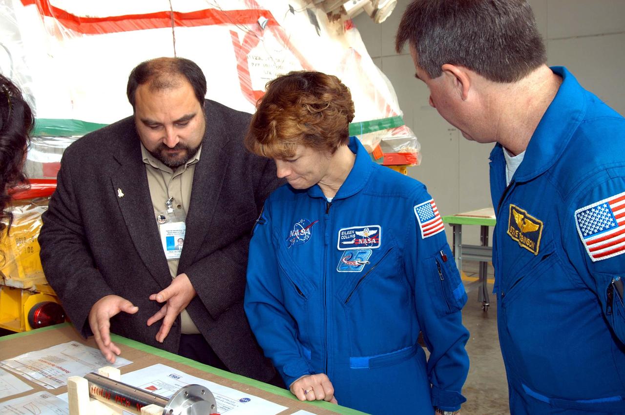 KENNEDY SPACE CENTER, FLA. -  At the SRB Assembly and Refurbishment Facility, STS-114 Eileen Collins (center) and Mission Specialist Stephen Robinson look on the table at a mockup of a booster separation motor (BSM) igniter and expanded views of the BSM and igniter.  At left is Paul Gutierrez,  SRB associate program manager with United Space Alliance.  The crew is at KSC for familiarization with Shuttle and mission equipment. The STS-114 mission is Logistics Flight 1, which is scheduled to deliver supplies and equipment, plus the external stowage platform, to the International Space Station.