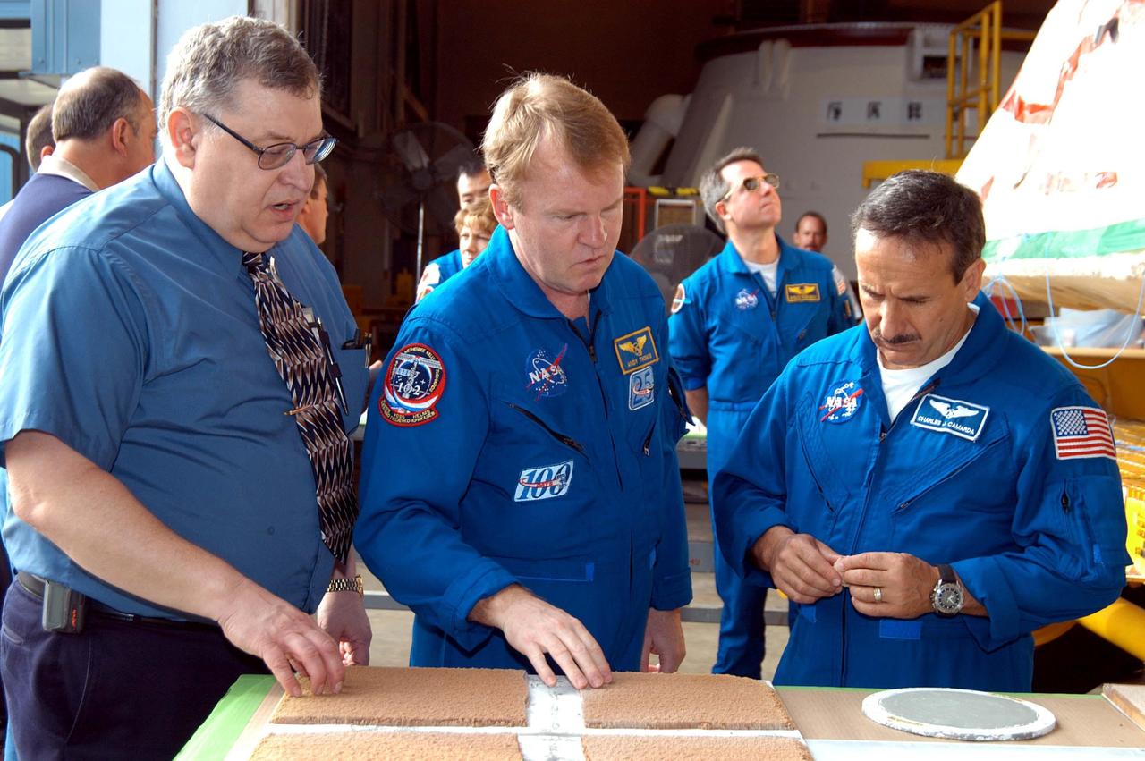 KENNEDY SPACE CENTER, FLA. -  At the SRB Assembly and Refurbishment Facility, STS-114 Mission Specialists Andrew Thomas (center) and Charles Camarda (right) look at a test panel of insulation material (left) cut in a liquid nitrogen process and a round aft heat seal (right) also treated in a liquid nitrogen process. At left is Mike Leppert, Manufacturing Operations project lead with United Space Alliance.  The crew is at KSC for familiarization with Shuttle and mission equipment. The STS-114 mission is Logistics Flight 1, which is scheduled to deliver supplies and equipment, plus the external stowage platform, to the International Space Station.