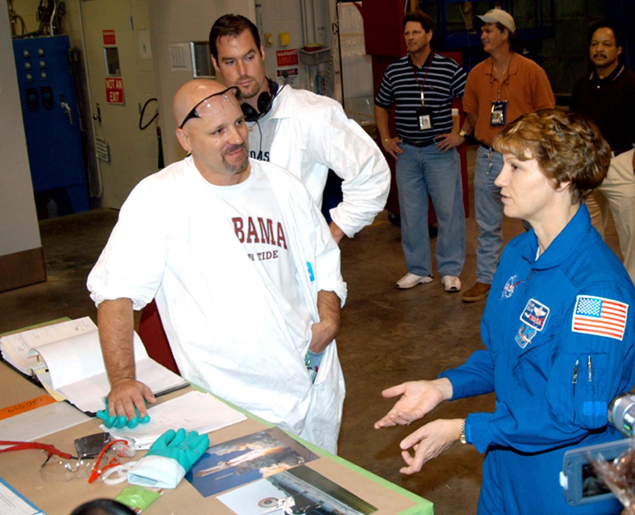 KENNEDY SPACE CENTER, FLA. - In the SRB Assembly and Refurbishment Facility, STS-114 Commander Eileen Collins (right) talks with Tim Hamilton (front) and Brett Schultheis (behind), thermal protection system technicians with United Space Alliance. The crew is at KSC for familiarization with Shuttle and mission equipment. The STS-114 mission is Logistics Flight 1, which is scheduled to deliver supplies and equipment, plus the external stowage platform, to the International Space Station.
