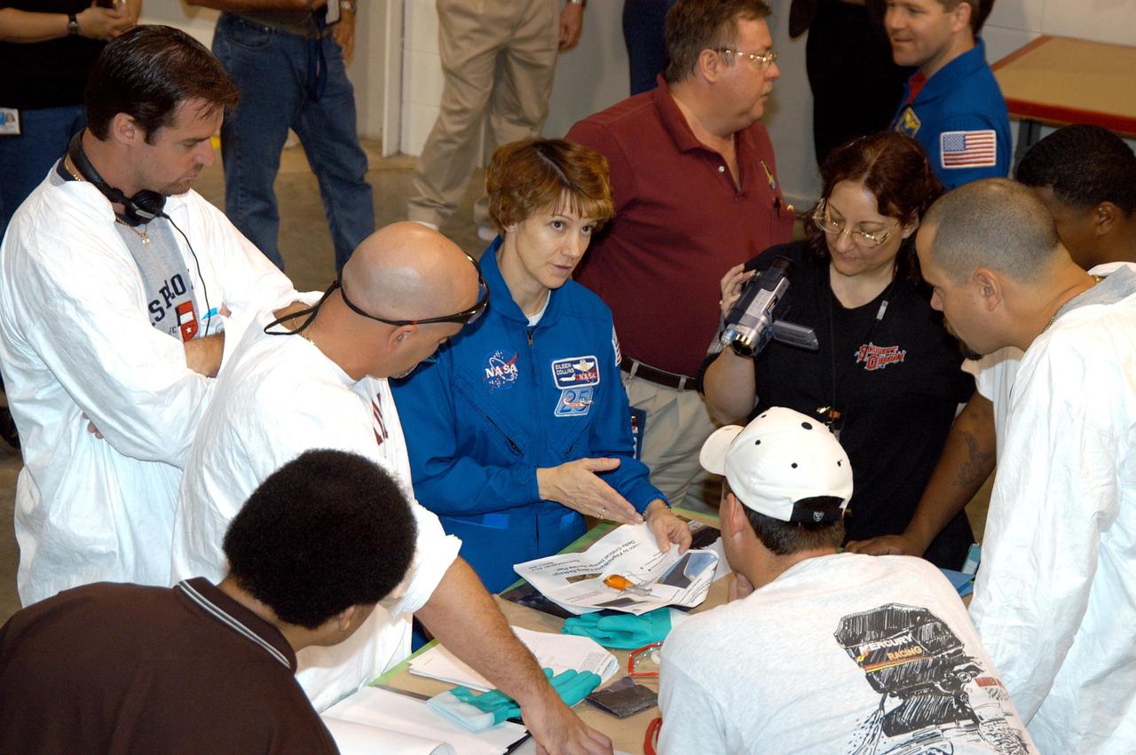 KENNEDY SPACE CENTER, FLA. -  In the SRB Assembly and Refurbishment Facility, STS-114 Commander Eileen Collins (center) asks the thermal protection system technicians questions about work they are doing. The crew is at KSC for familiarization with Shuttle and mission equipment. The STS-114 mission is Logistics Flight 1, which is scheduled to deliver supplies and equipment, plus the external stowage platform, to the International Space Station.