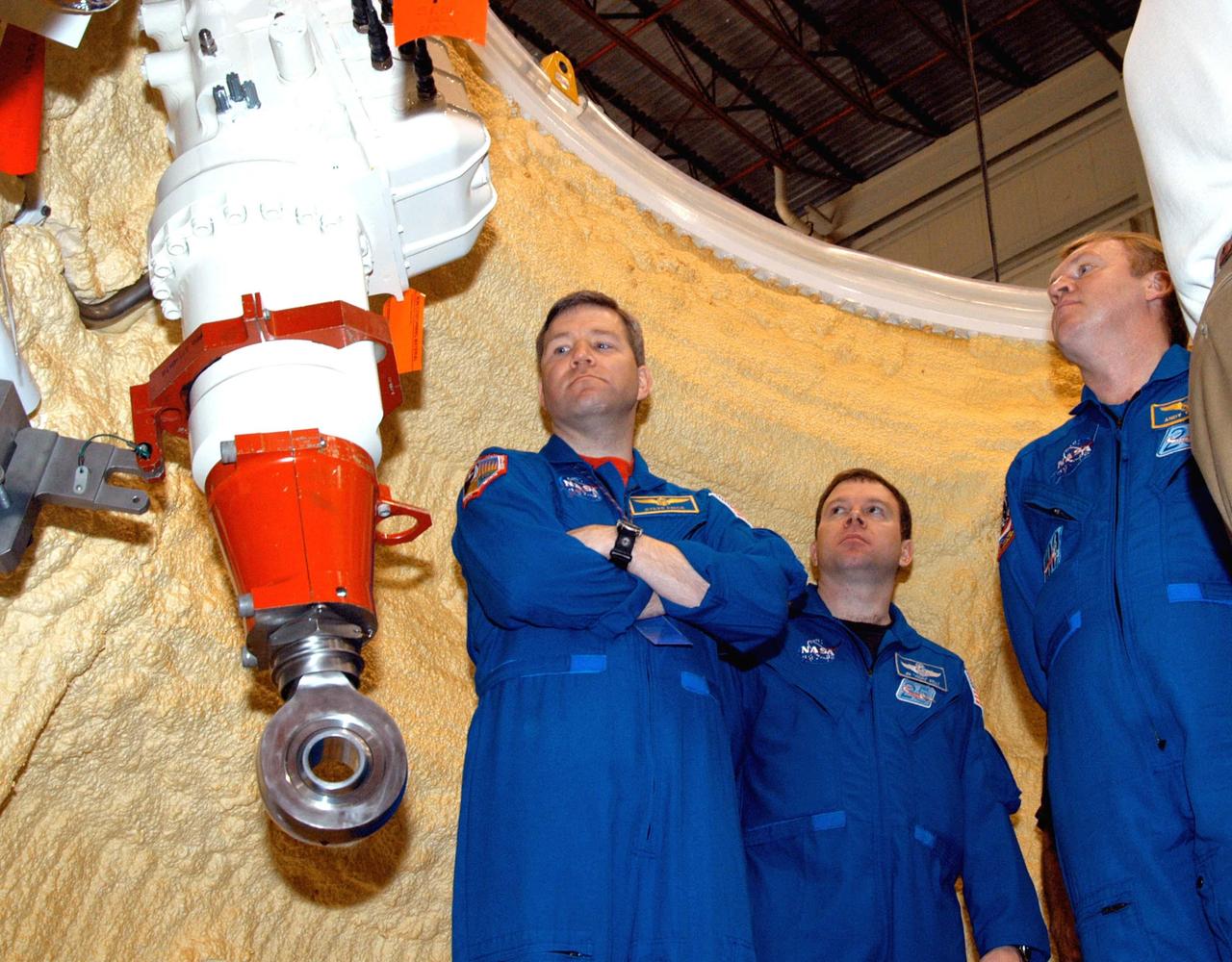KENNEDY SPACE CENTER, FLA. -  In the SRB Assembly and Refurbishment Facility, members of the STS-114 crew get a close look at an actuator, part of the thrust vector control system, in a segment of a solid rocket booster.  Behind them is the yellow foam insulation. At left is astronaut Steven Frick; in the center is STS-114 Pilot James Kelly and, at right, is Mission Specialist Andrew Thomas.  The crew is at KSC for familiarization with Shuttle and mission equipment. The STS-114 mission is Logistics Flight 1, which is scheduled to deliver supplies and equipment, plus the external stowage platform, to the International Space Station.