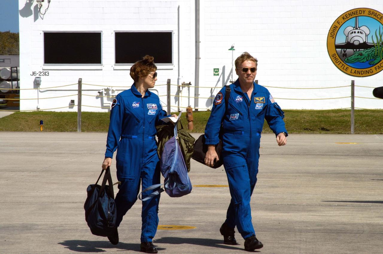 KENNEDY SPACE CENTER, FLA. - STS-114 Commander Eileen Collins and Mission Specialist Andrew Thomas cross the Shuttle Landing Facility toward the planes that will return them to Houston.  Crew members were at KSC for Shuttle and mission equipment familiarization.  The STS-114 mission is Logistics Flight 1, which is scheduled to deliver supplies and equipment, plus the external stowage platform, to the International Space Station.