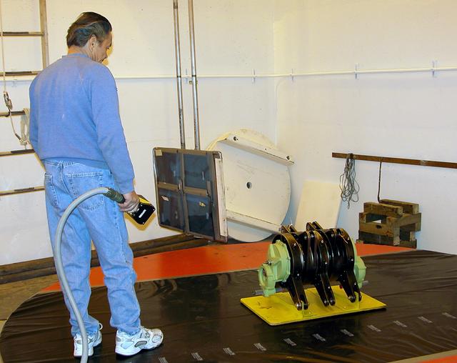 NASA image: KENNEDY SPACE CENTER, FLA. -  A rudder speed brake actuator sits on an air-bearing pallet to undergo X-raying.  Four actuators to be installed on the orbiter Discovery are being X-rayed at the Radiographic High-Energy X-ray Facility to determine if the gears were installed correctly. Discovery has been assigned to the first Return to Flight mission, STS-114, a logistics flight to the International Space Station.