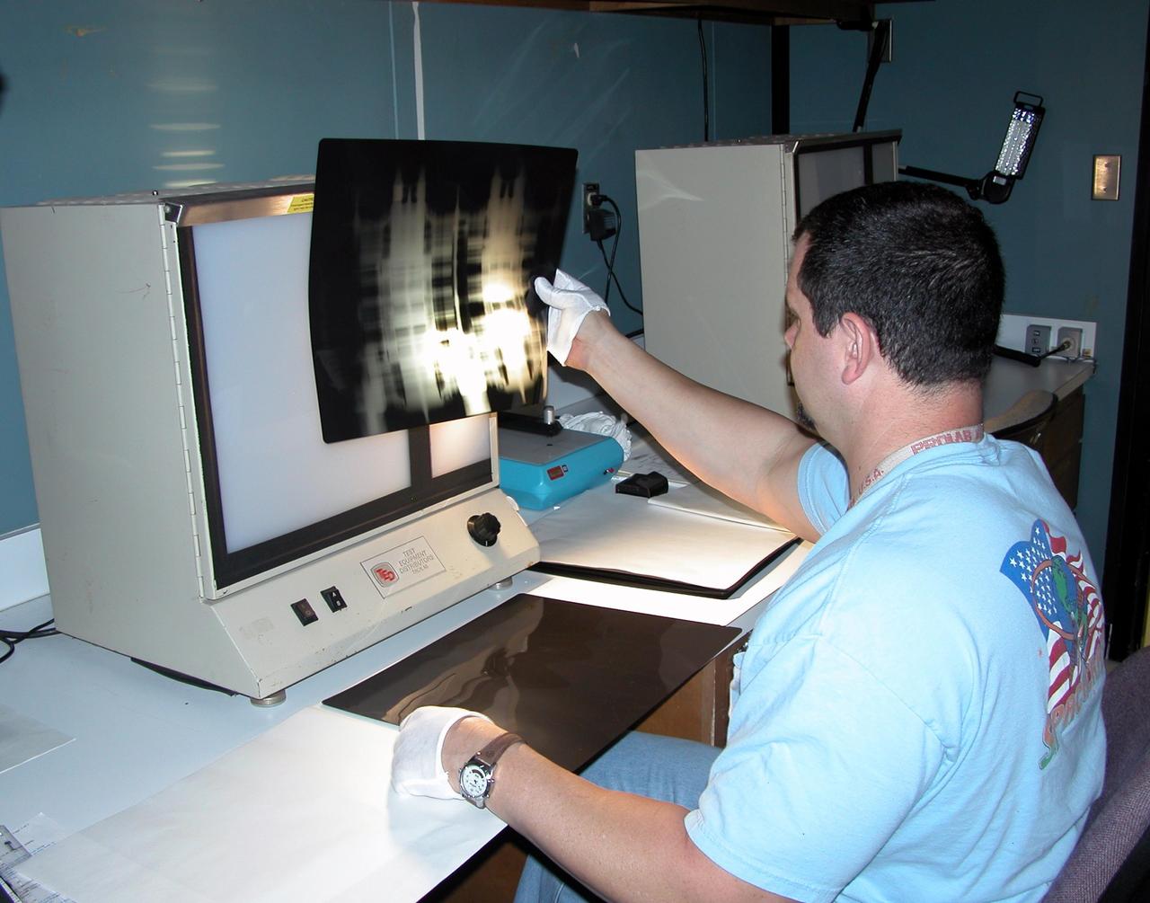 KENNEDY SPACE CENTER, FLA. -  A technician at Cape Canaveral Air Force Station’s Radiographic High-Energy X-ray Facility looks at an X-ray of one of the four rudder speed brake actuators to be installed on the orbiter Discovery.  The actuators are being X-rayed to determine if the gears were installed correctly. Discovery has been assigned to the first Return to Flight mission, STS-114, a logistics flight to the International Space Station.