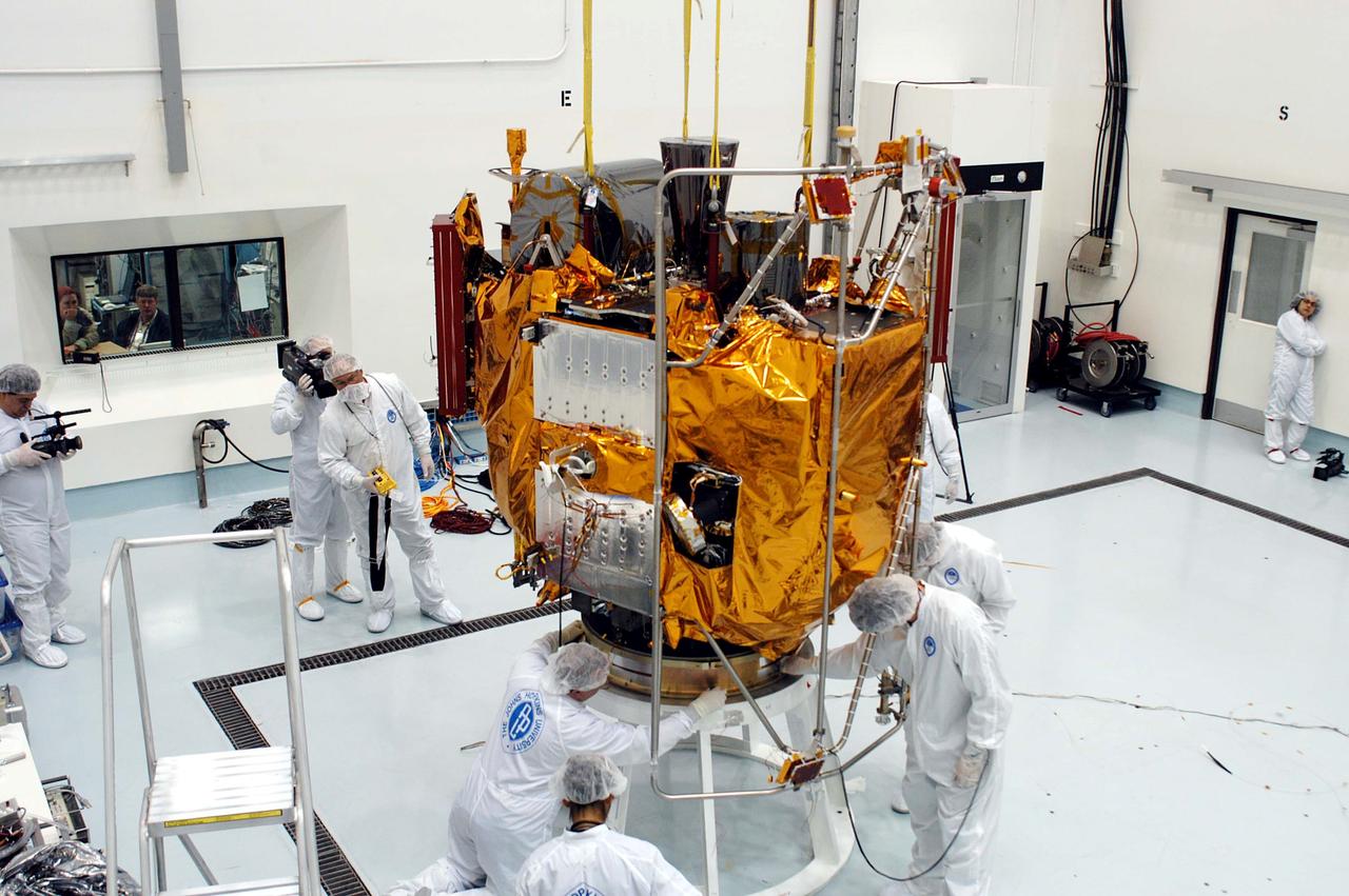 KENNEDY SPACE CENTER, FLA. -  At the Astrotech Space Operations processing facilities, workers check the placement of NASA’s MESSENGER spacecraft on a work stand. There employees of the Johns Hopkins University Applied Physics Laboratory, builders of the spacecraft, will perform an initial state-of-health check.  Then processing for launch can begin, including checkout of the power systems, communications systems and control systems.  The thermal blankets will also be attached for flight.  MESSENGER - short for MErcury Surface, Space ENvironment, GEochemistry and Ranging - will be launched May 11 on a six-year mission aboard a Boeing Delta II rocket.  Liftoff is targeted for 2:26 a.m. EDT on Tuesday, May 11.