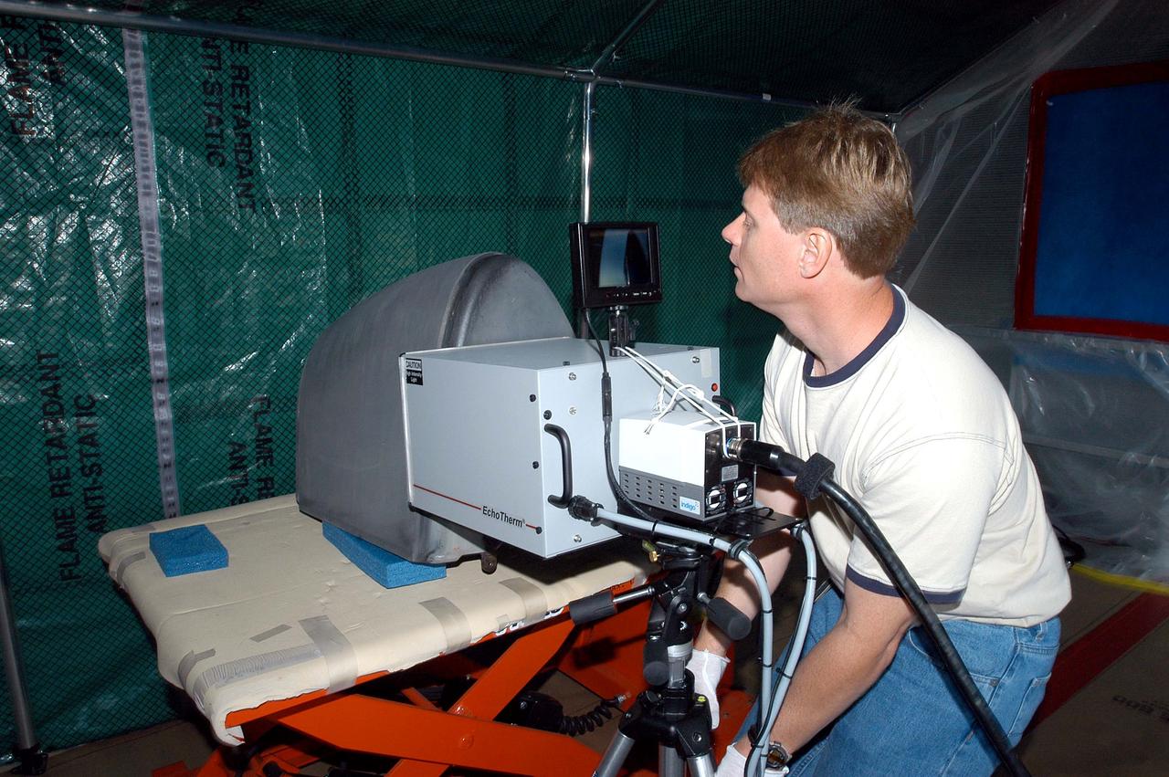 KENNEDY SPACE CENTER, FLA. -  Jim Landy, NDE specialist with United Space Alliance (USA), examines a Reinforced Carbon Carbon panel using flash thermography.  A relatively new procedure at KSC, thermography uses high intensity light to heat areas of the panels. The panels are then immediately scanned with an infrared camera. As the panels cool, any internal flaws are revealed. The gray carbon composite RCC panels are attached to the leading edge of the wing of the orbiters.  They have sufficient strength to withstand the aerodynamic forces experienced during launch and reentry, which can reach as high as 800 pounds per square foot.  The operating range of RCC is from minus 250º F to about 3,000º F, the temperature produced by friction with the atmosphere during reentry.  The panels will be installed on the orbiter Discovery, designated for the first Return to Flight mission, STS-114.