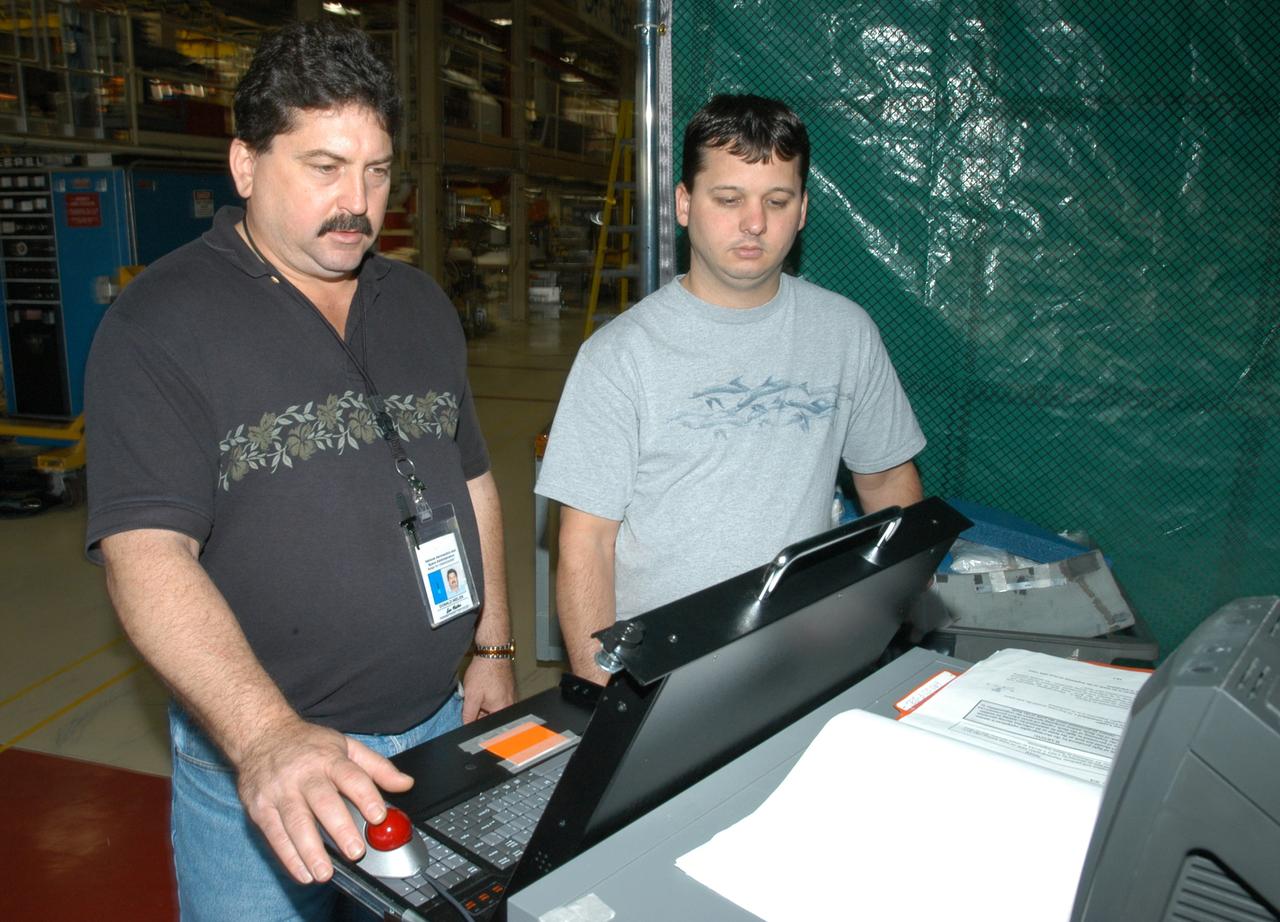 KENNEDY SPACE CENTER, FLA. -  Dan Phillips (left) and Donald Nielen, with United Space Alliance, look at the results of flash thermography on a Reinforced Carbon Carbon panel.  A relatively new procedure at KSC, thermography uses high intensity light to heat areas of the panels. The panels are then immediately scanned with an infrared camera. As the panels cool, any internal flaws are revealed. The gray carbon composite RCC panels are attached to the leading edge of the wing of the orbiters.  They have sufficient strength to withstand the aerodynamic forces experienced during launch and reentry, which can reach as high as 800 pounds per square foot.  The operating range of RCC is from minus 250º F to about 3,000º F, the temperature produced by friction with the atmosphere during reentry.  The panels will be installed on the orbiter Discovery, designated  for the first Return to Flight mission, STS-114.