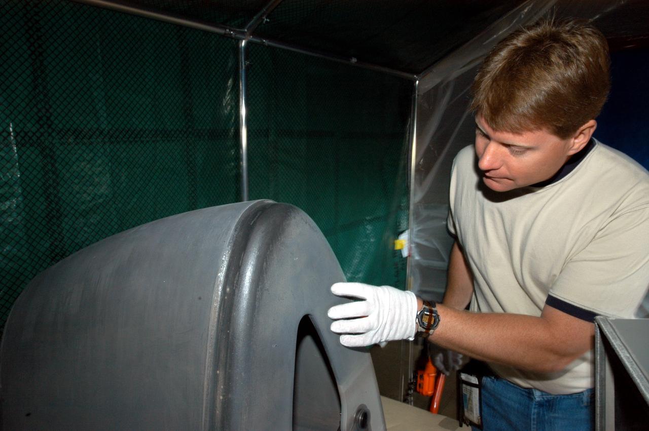 KENNEDY SPACE CENTER, FLA. -  Jim Landy, NDE specialist with USA, looks closely at an area of a Reinforced Carbon Carbon panel just examined using flash thermography. A relatively new procedure at KSC, thermography uses high intensity light to heat areas of the panels. The panels are then immediately scanned with an infrared camera. As the panels cool, any internal flaws are revealed. The gray carbon composite RCC panels are attached to the leading edge of the wing of the orbiters.  They have sufficient strength to withstand the aerodynamic forces experienced during launch and reentry, which can reach as high as 800 pounds per square foot.  The operating range of RCC is from minus 250º F to about 3,000º F, the temperature produced by friction with the atmosphere during reentry.  The panels will be installed on the orbiter Discovery, designated for the first Return to Flight mission, STS-114.