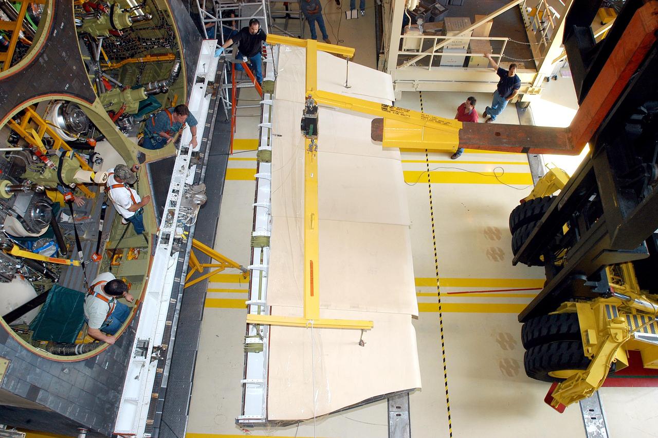 KENNEDY SPACE CENTER, FLA. -  In the Orbiter Processing Facility, the body flap is moved into position for installation on the orbiter Discovery.  The body flap is an aluminum structure consisting of ribs, spars, skin panels and a trailing edge assembly. It thermally shields the three main engines during entry and provides pitch control trim during landing approach.  Discovery is being processed for launch on the first Return to Flight mission, STS-114.
