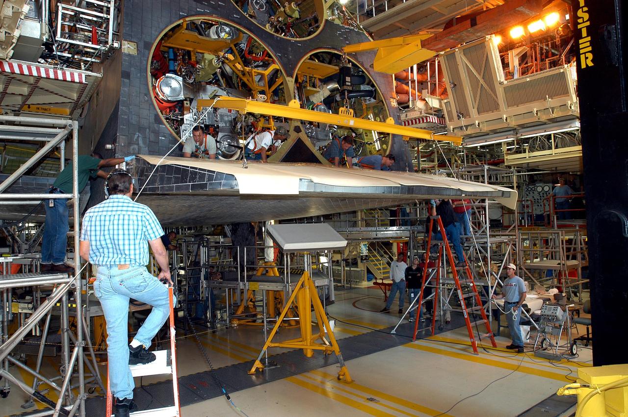 KENNEDY SPACE CENTER, FLA. -  Workers on ladders (left and right) check installation of the body flap onto the orbiter Discovery. The body flap is an aluminum structure consisting of ribs, spars, skin panels and a trailing edge assembly. It thermally shields the three main engines during entry and provides pitch control trim during landing approach. Discovery is being processed for launch on the first Return to Flight mission, STS-114.