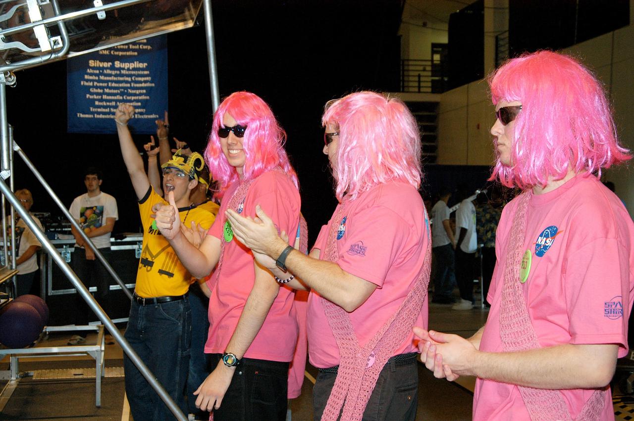 KENNEDY SPACE CENTER, FLA. -  During the 2004 Florida Regional FIRST competition in the University of Central Florida Arena, the KSC-sponsored “Pink” team applauds a win by the yellow-clad Central Florida team. The event hosted 41 teams from Canada, Brazil, Great Britain and the United States.  Among observers at the annual event were Center Director Jim Kennedy and Florida Gov. Jeb Bush, who spoke at the event luncheon.  FIRST is a nonprofit organization, For Inspiration and Recognition of Science and Technology, that sponsors the event pitting gladiator robots against each other in an athletic-style competition. The FIRST robotics competition is designed to provide students with a hands-on, inside look at engineering and other professional careers, pairing high school students with engineer mentors and corporations.