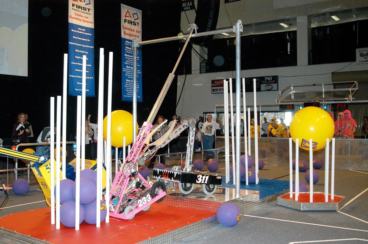 KENNEDY SPACE CENTER, FLA. -  Robots of the KSC-sponsored “Pink” team and yellow-clad Central Florida team vie for points on the floor of the University of Central Florida Arena during the 2004 Florida Regional FIRST competition. The event hosted 41 teams from Canada, Brazil, Great Britain and the United States.  Among observers at the annual event were Center Director Jim Kennedy and Florida Gov. Jeb Bush, who spoke at the event luncheon.  FIRST is a nonprofit organization, For Inspiration and Recognition of Science and Technology, that sponsors the event pitting gladiator robots against each other in an athletic-style competition. The FIRST robotics competition is designed to provide students with a hands-on, inside look at engineering and other professional careers, pairing high school students with engineer mentors and corporations.