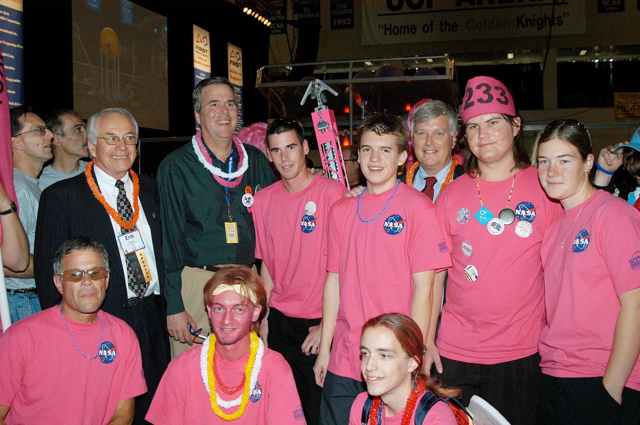 KENNEDY SPACE CENTER, FLA. -  The KSC-sponsored “Pink” team poses for a photo with Florida Gov. Jeb Bush (second from left) during a break at the 2004 Florida Regional FIRST competition, held at the University of Central Florida.  The annual event is hosting 41 teams from Canada, Brazil, Great Britain and the United States. FIRST is a nonprofit organization, For Inspiration and Recognition of Science and Technology, that sponsors the event pitting robots against each other in an athletic-style competition. The FIRST robotics competition is designed to provide students with a hands-on, inside look at engineering and other professional careers, pairing high school students with engineer mentors and corporations.