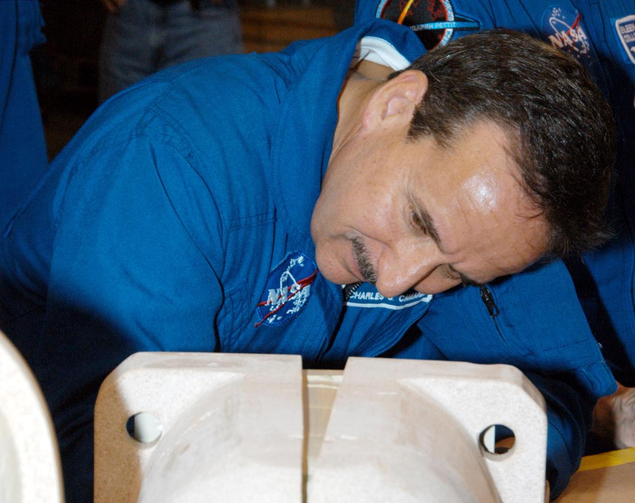 KENNEDY SPACE CENTER, FLA. -  In the SRB Assembly and Refurbishment Facility,  STS-114 Mission Specialist Charles Camarda looks closely at a test design of the bolt catcher insulation.  The STS-114 crew is at KSC for familiarization with Shuttle and mission equipment. The mission is Logistics Flight 1, which is scheduled to deliver supplies and equipment, plus the external stowage platform, to the International Space Station.