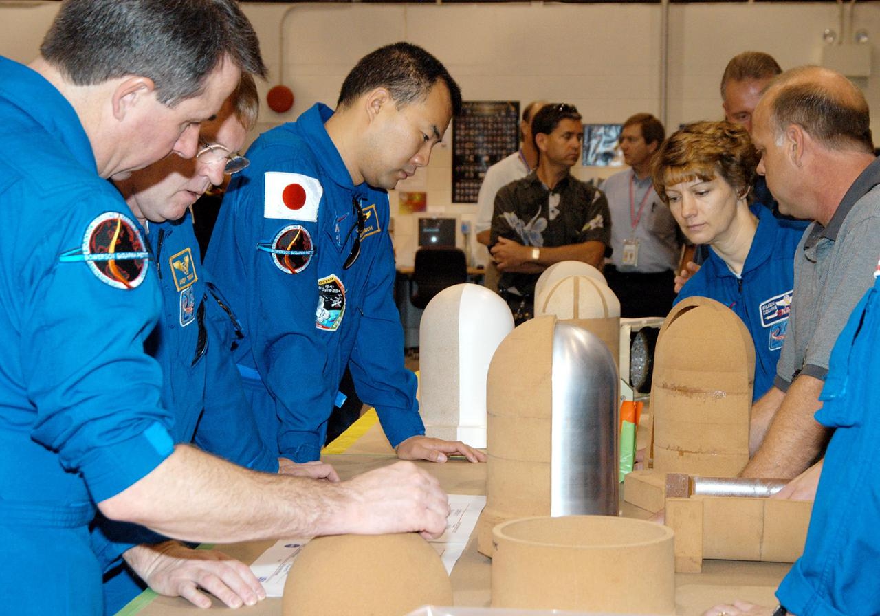 KENNEDY SPACE CENTER, FLA. -  In the SRB Assembly and Refurbishment Facility,  STS-114 crew members look at test designs of the bolt catcher insulation.  Starting from left are Mission Specialists Stephen Robinson, Andrew Thomas and Soichi Noguchi; and Commander Eileen Collins.  The STS-114 crew is at KSC for familiarization with Shuttle and mission equipment. The mission is Logistics Flight 1, which is scheduled to deliver supplies and equipment, plus the external stowage platform, to the International Space Station.