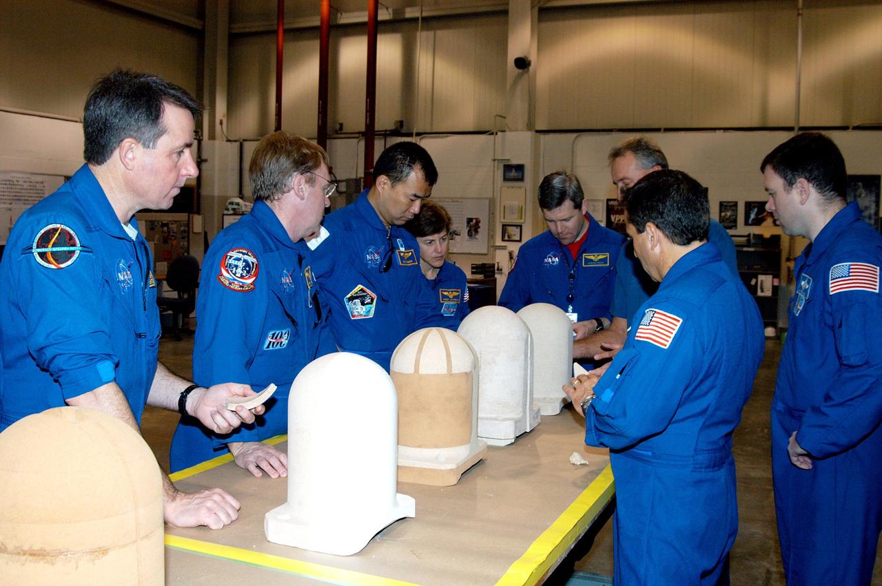 KENNEDY SPACE CENTER, FLA. -  In the SRB Assembly and Refurbishment Facility,  STS-114 crew members look at test designs of the bolt catcher insulation.  Starting from left are Mission Specialists Stephen Robinson, Andrew Thomas, Soichi Noguchi and Wendy Lawrence; astronaut Steven Frick;  Mission Specialist Charles Camarda (back to camera); and Pilot James Kelly.  Noguchi represents the Japanese Aerospace and Exploration Agency.  The STS-114 crew is at KSC for familiarization with Shuttle and mission equipment. The mission is Logistics Flight 1, which is scheduled to deliver supplies and equipment, plus the external stowage platform, to the International Space Station.