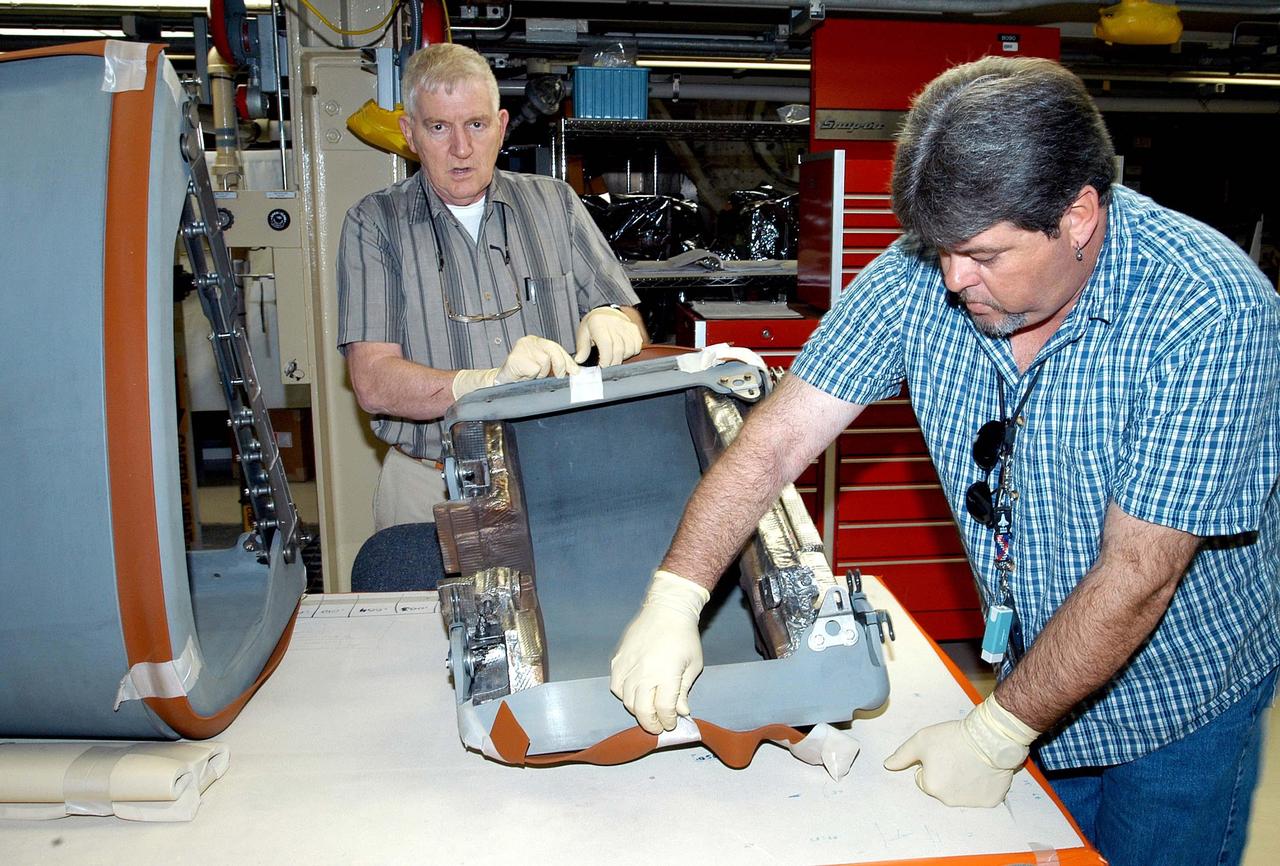 KENNEDY SPACE CENTER, FLA. -  In the Orbiter Processing Facility, United Space Alliance technicians Jim Burgess (left) and Dave Fuller (right) prepare the first Reinforced Carbon-Carbon panel for installation on the left wing leading edge on Discovery. The RCC panels are mechanically attached to the wing with spars, a series of floating joints to reduce loading on the panels caused by wing deflections. Discovery has been named as the orbiter to fly on the first Return to Flight mission, STS-114.