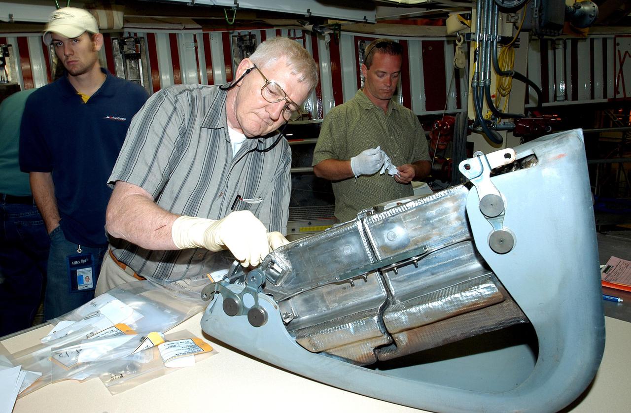 KENNEDY SPACE CENTER, FLA. -  In the Orbiter Processing Facility, United Space Alliance technician Jim Burgess (right) works on the first Reinforced Carbon-Carbon panel to be installed on the left wing leading edge on Discovery.  At left is USA technician Dave Fuller.  The RCC panels are mechanically attached to the wing with spars, a series of floating joints to reduce loading on the panels caused by wing deflections.  Discovery has been named as the orbiter to fly on the first Return to Flight mission, STS-114.