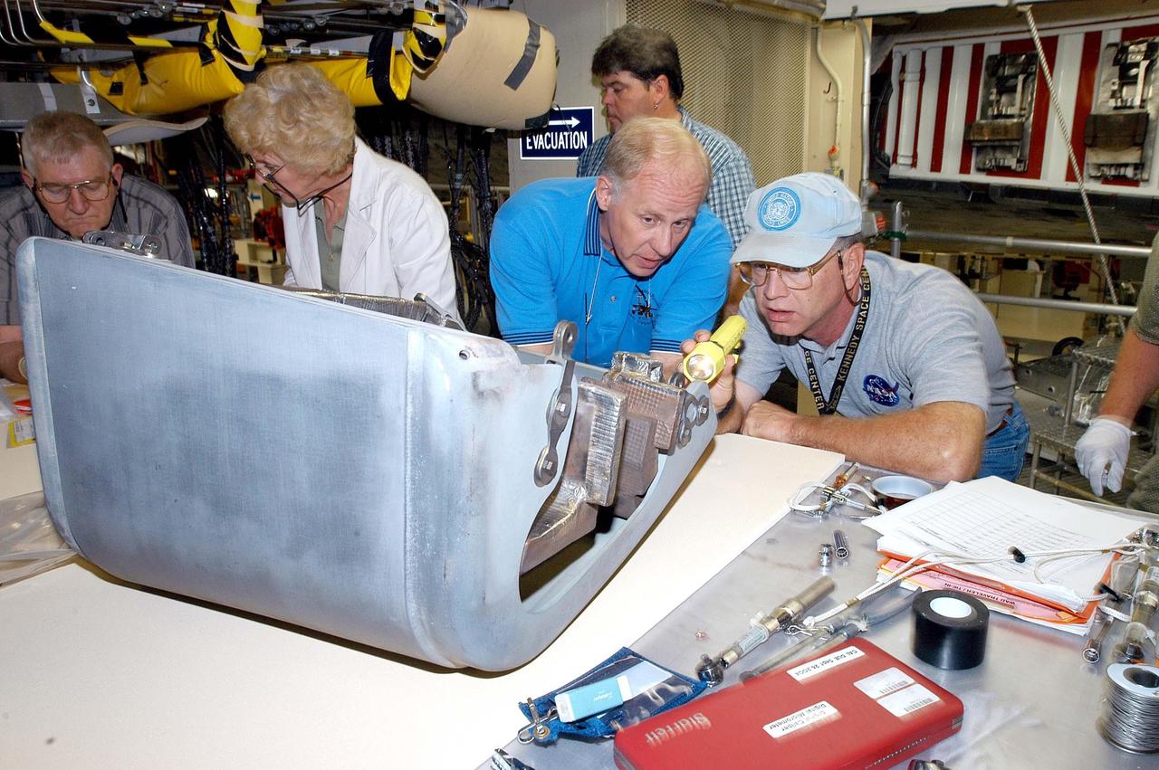 KENNEDY SPACE CENTER, FLA. -  In the Orbiter Processing Facility, Danny Wyatt, NASA Quality Assurance specialist, and John Legere (right), NASA Quality Assurance specialist, examine the first Reinforced Carbon-Carbon panel to be installed on the left wing leading edge on Discovery. The RCC panels are mechanically attached to the wing with spars, a series of floating joints to reduce loading on the panels caused by wing deflections. Discovery has been named as the orbiter to fly on the first Return to Flight mission, STS-114.