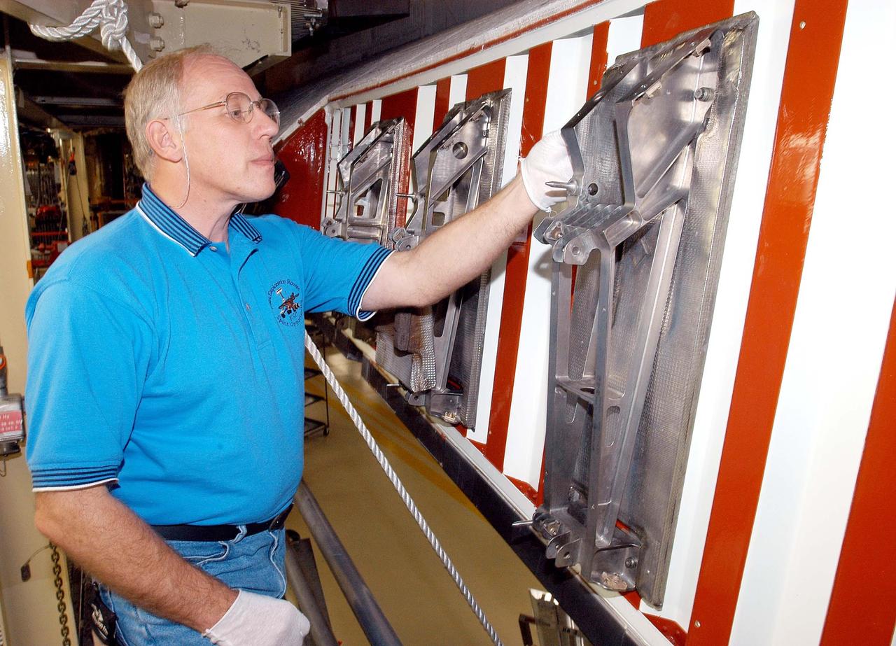 KENNEDY SPACE CENTER, FLA. -  In the Orbiter Processing Facility, Danny Wyatt, NASA Quality Assurance specialist, examines the attachment point for the first Reinforced Carbon-Carbon panel to be installed on the left wing leading edge of Discovery.  The RCC panels are mechanically attached to the wing with spars, a series of floating joints to reduce loading on the panels caused by wing deflections. Discovery has been named as the orbiter to fly on the first Return to Flight mission, STS-114.
