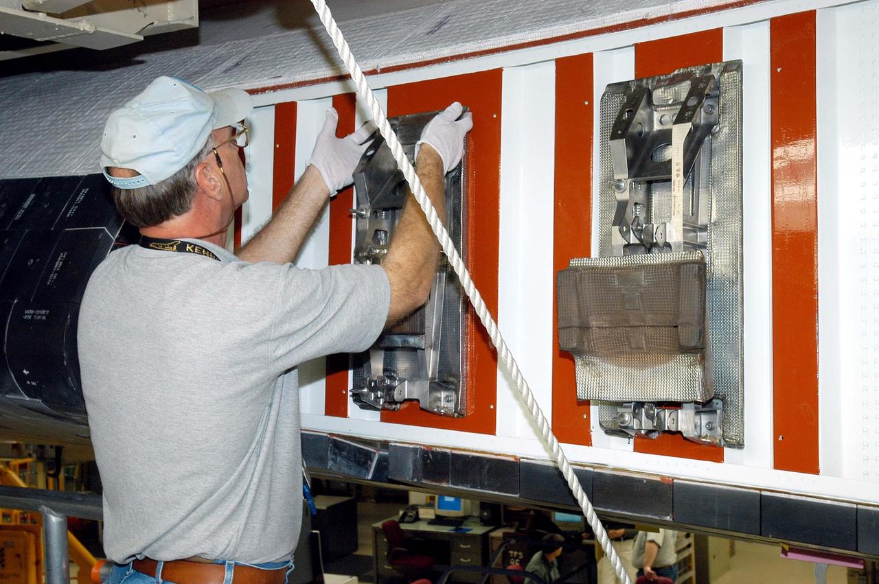 KENNEDY SPACE CENTER, FLA. -  In the Orbiter Processing Facility, John Legere, NASA Quality Assurance specialist, examines the attachment point for the first Reinforced Carbon-Carbon panel to be installed on the left wing leading edge of Discovery.  The RCC panels are mechanically attached to the wing with spars, a series of floating joints to reduce loading on the panels caused by wing deflections. Discovery has been named as the orbiter to fly on the first Return to Flight mission, STS-114.