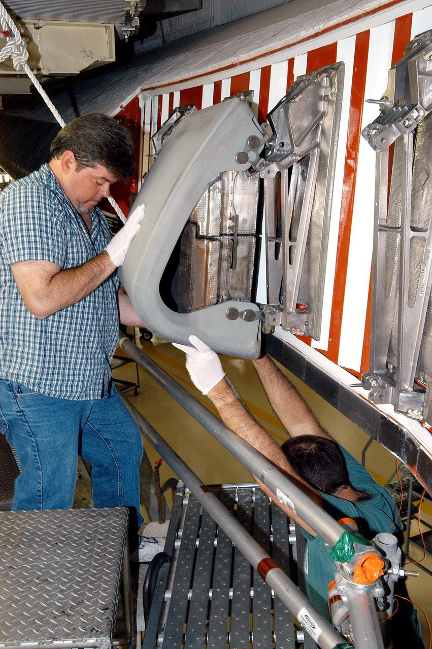 KENNEDY SPACE CENTER, FLA. -  In the Orbiter Processing Facility, United Space Alliance technician Dave Fuller installs the first Reinforced Carbon-Carbon panel on the left wing leading edge of Discovery. The RCC panels are mechanically attached to the wing with spars, a series of floating joints to reduce loading on the panels caused by wing deflections.  Discovery has been named as the orbiter to fly on the first Return to Flight mission, STS-114.