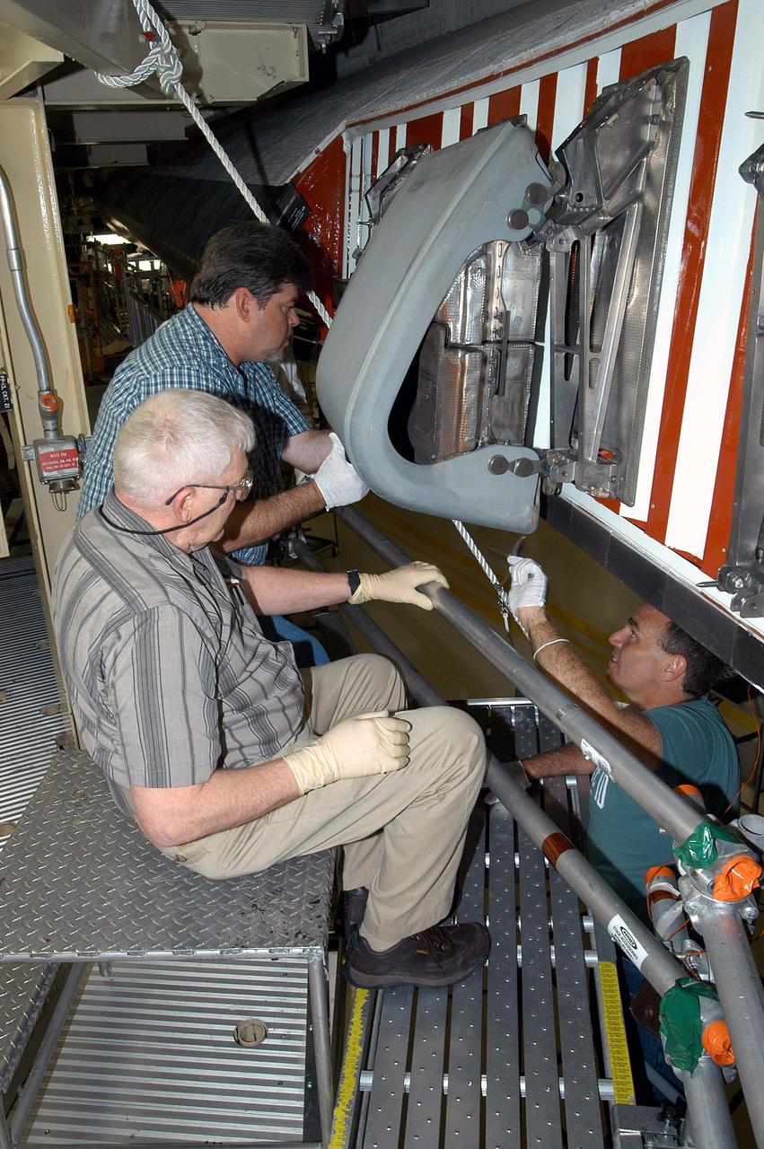 KENNEDY SPACE CENTER, FLA. -  In the Orbiter Processing Facility, United Space Alliance technicians Dave Fuller (rear) and Jim Burgess (front) continue installing the first Reinforced Carbon-Carbon panel on the left wing leading edge of Discovery. The RCC panels are mechanically attached to the wing with spars, a series of floating joints to reduce loading on the panels caused by wing deflections. Discovery has been named as the orbiter to fly on the first Return to Flight mission, STS-114.