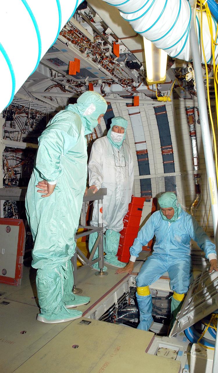 KENNEDY SPACE CENTER, FLA. -  In the middeck of Endeavour, in the Orbiter Processing Facility, Center Director Jim Kennedy (far left) watches as a technician gets ready to lower himself through the LiOH door into the Environmental Control and Life Support System (ECLSS) bay. LiOH refers to lithium hydroxide, canisters of which are stored in the ECLSS bay under the middeck floor. During flight, cabin air from the cabin fan is ducted to two LiOH canisters, where carbon dioxide is removed and activated charcoal removes odors and trace contaminants.  Kennedy is taking an opportunity to learn first-hand what workers are doing to enable Return to Flight.  Endeavour is in an Orbiter Major Modification period.