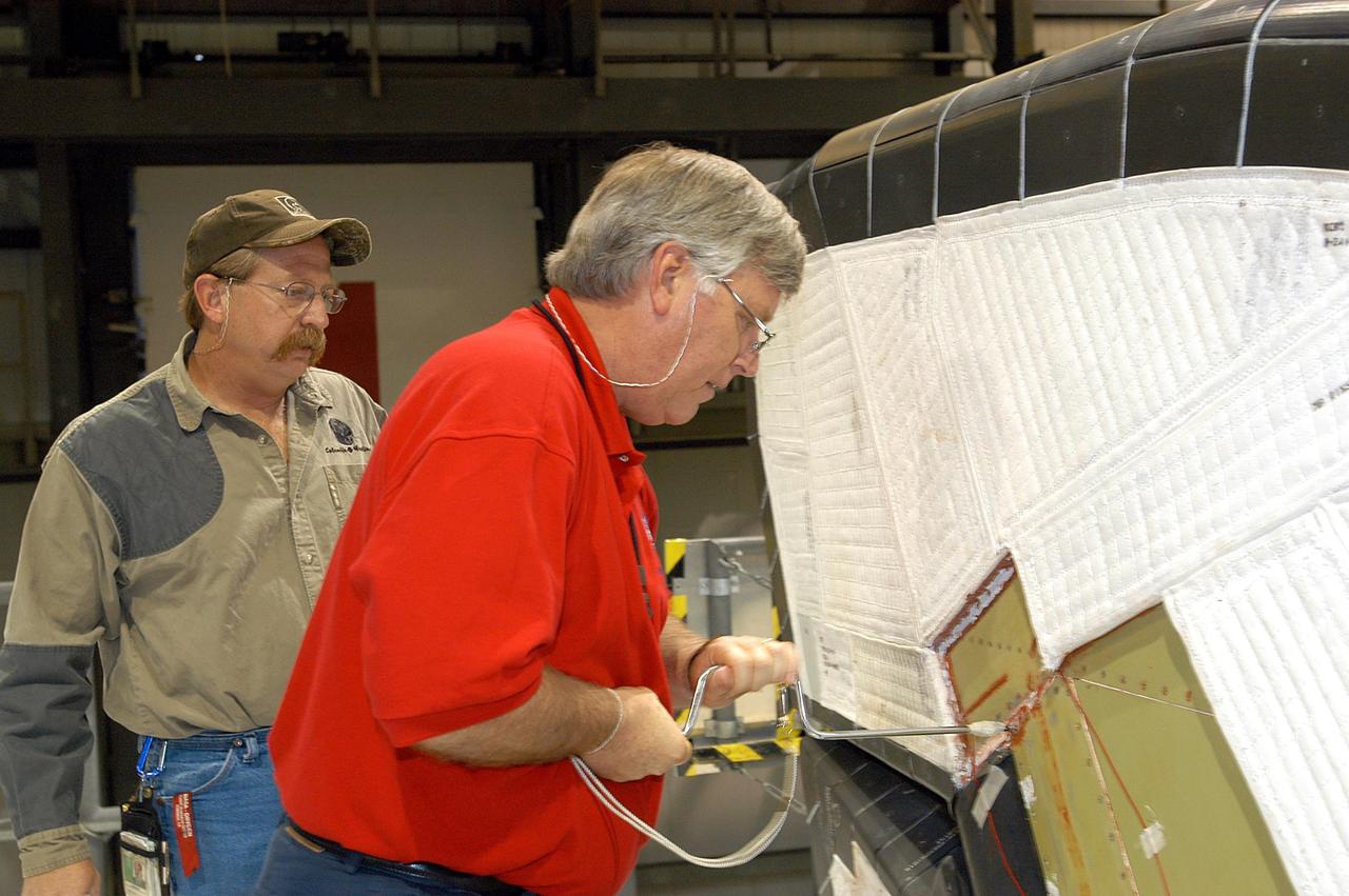 KENNEDY SPACE CENTER, FLA. -  Under a worker’s watchful eyes in the Orbiter Processing Facility, Center Director Jim Kennedy (right) takes a turn on a screw on Endeavour.  Kennedy is taking an opportunity to learn first-hand what workers are doing to enable Return to Flight.  Endeavour is in an Orbiter Major Modification period.