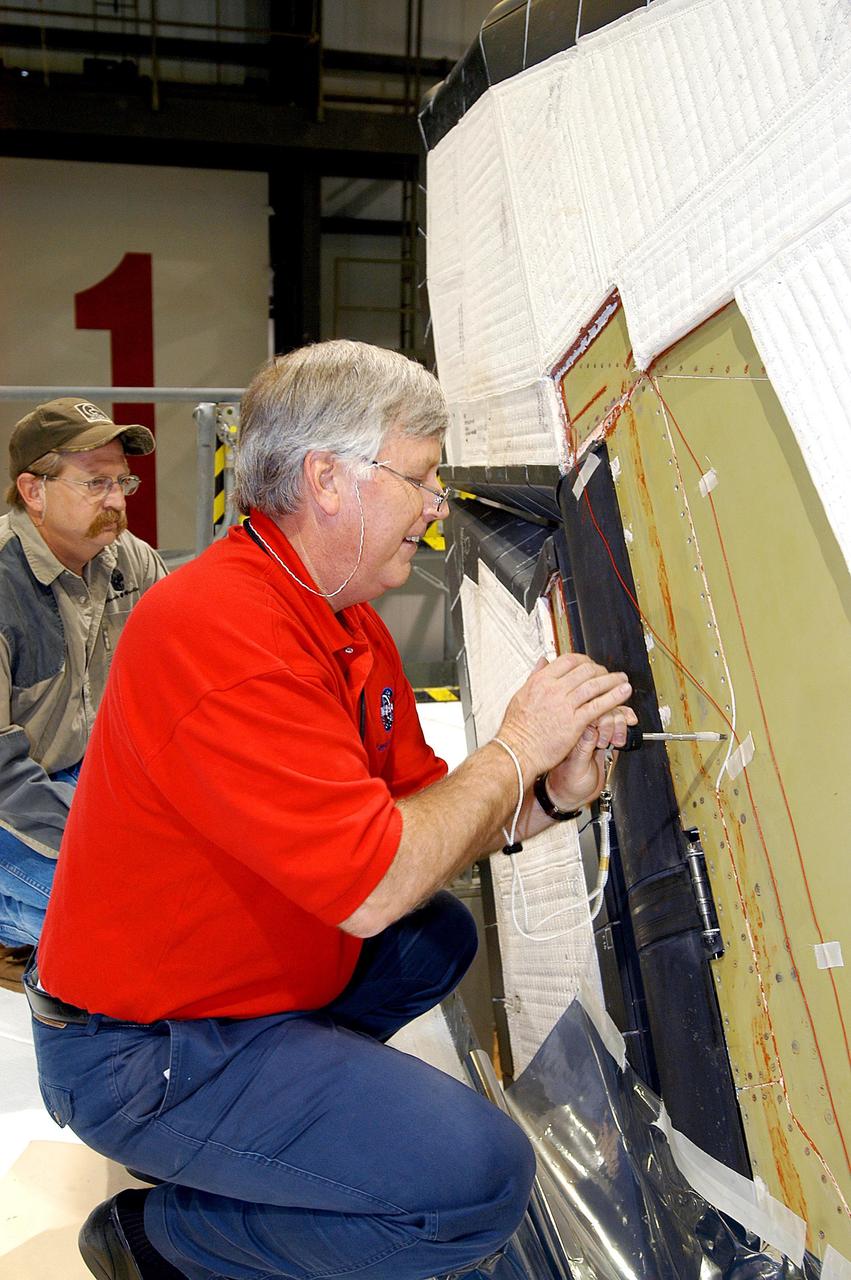 KENNEDY SPACE CENTER, FLA. -  Under a worker’s watchful eyes in the Orbiter Processing Facility, Center Director Jim Kennedy (right) takes a turn on a screw on Endeavour.  Kennedy is taking an opportunity to learn first-hand what workers are doing to enable Return to Flight.  Endeavour is in an Orbiter Major Modification period.