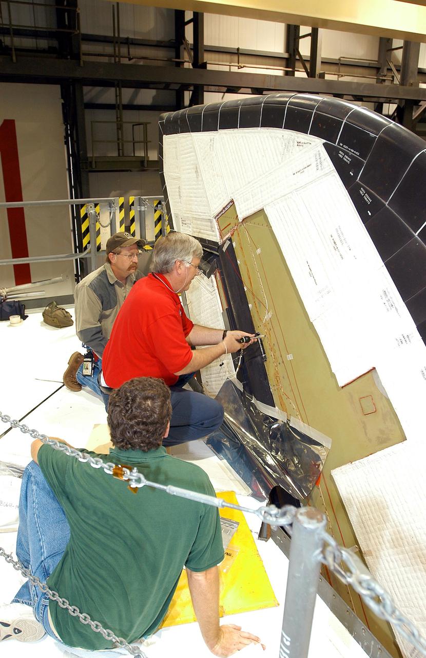 KENNEDY SPACE CENTER, FLA. -  Under workers’ watchful eyes in the Orbiter Processing Facility, Center Director Jim Kennedy (center) takes a turn on a screw on Endeavour.  Kennedy is taking an opportunity to learn first-hand what workers are doing to enable Return to Flight.  Endeavour is in an Orbiter Major Modification period.