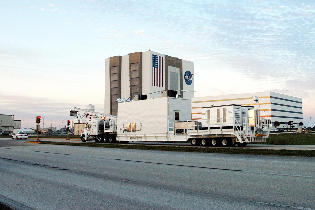 KENNEDY SPACE CENTER, FLA. -  A Universal Coolant Transporter (UCT), manufactured  in Sharpes, Fla., drives past the Vehicle Assembly Building (background, left) and Operations Support Building (background, right) on its way to the KSC Shuttle Landing Facility (SLF).  Replacing the existing ground cooling unit, the UCT is designed to service payloads for the Space Shuttle and International Space Station, and may be capable of servicing space exploration vehicles of the future.  It will provide ground cooling to the orbiter and returning payloads, such as science experiments requiring cold or freezing temperatures, during post-landing activities at the SLF and during transport of the payloads to other facilities.
