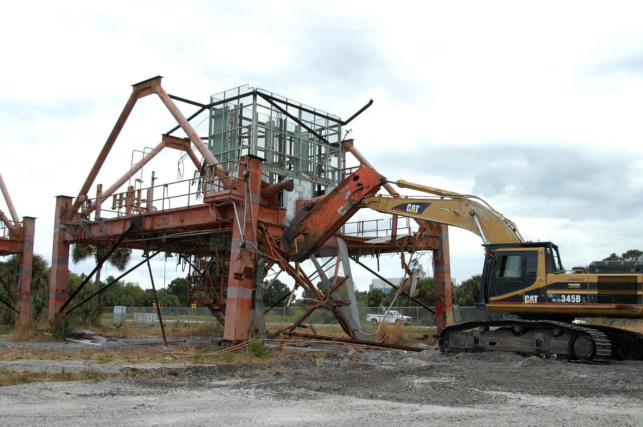 KENNEDY SPACE CENTER, FLA. -- Launch Umbilical Tower No. 1 (LUT-1), stored in the Industrial Area of KSC, is being demolished using a Caterpillar excavator and 48-inch shear attachment.  Seen is the base of tower; the upright tower extended more than 398 feet above the launch pad.  The LUT-1 was part of the launch system used for Apollo-Saturn V, launching Apollo 8, Apollo 11, Skylab manned missions and the Apollo-Soyuz Test Project.  The shear being used for demolition is one used in the deconstruction of the Twin Towers in New York City after 9/11.