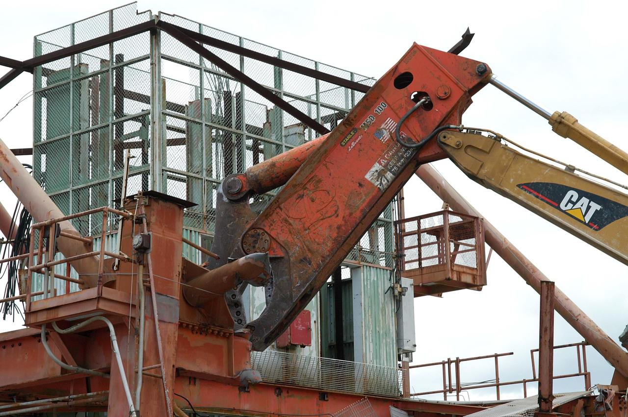 KENNEDY SPACE CENTER, FLA. -- Looking like a prehistoric monster crunching on its prey, the Caterpillar excavator and 48-inch shear attachment tear down Launch Umbilical Tower No. 1 (LUT-1) stored in the Industrial Area of KSC. The LUT-1 was part of the launch system used for Apollo-Saturn V, launching Apollo 8, Apollo 11, Skylab manned missions and the Apollo-Soyuz Test Project.   The shear is one used in the deconstruction of the Twin Towers in New York City after 9/11.