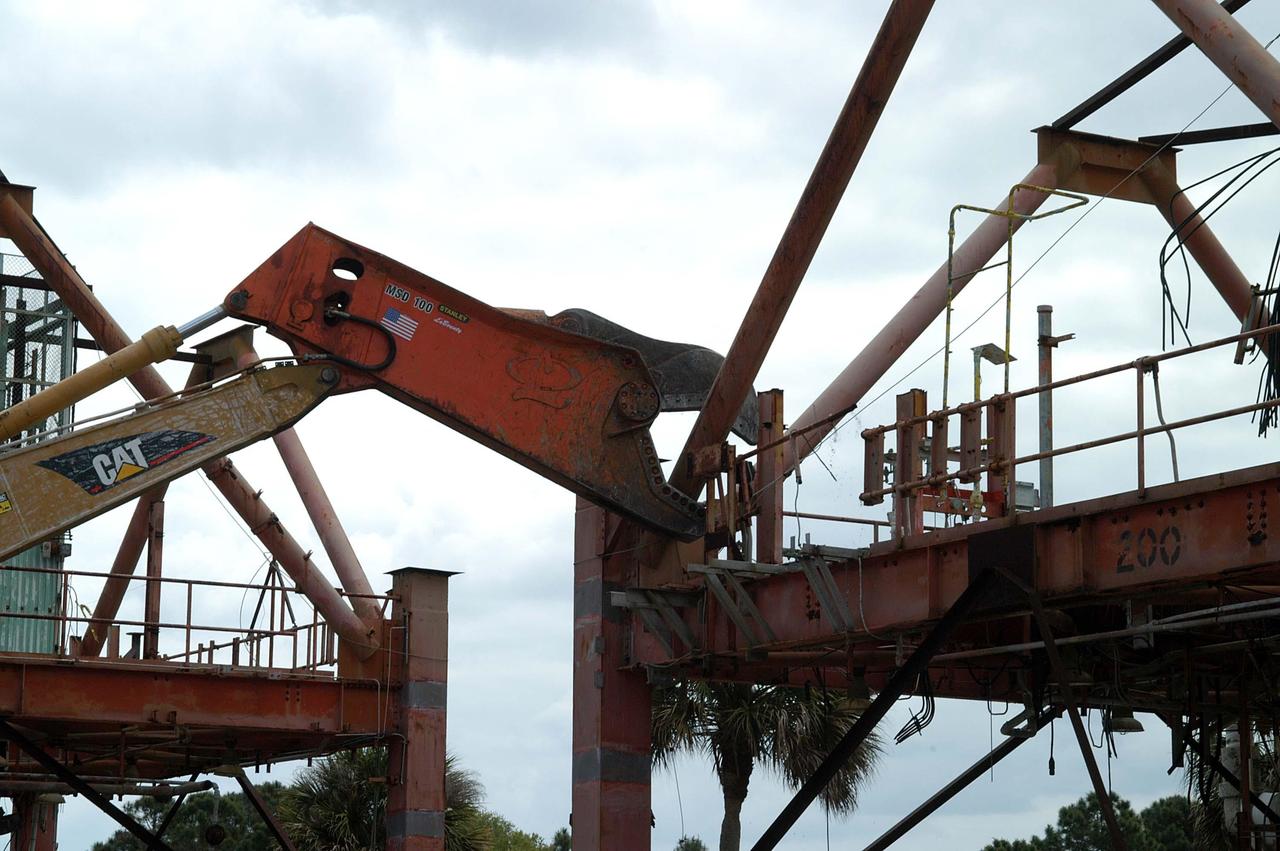 KENNEDY SPACE CENTER, FLA. -- Looking like a prehistoric monster crunching on its prey, the Caterpillar excavator and 48-inch shear attachment tear down Launch Umbilical Tower No. 1 (LUT-1) stored in the Industrial Area of KSC. The LUT-1 was part of the launch system used for Apollo-Saturn V, launching Apollo 8, Apollo 11, Skylab manned missions and the Apollo-Soyuz Test Project.   The shear is one used in the deconstruction of the Twin Towers in New York City after 9/11.