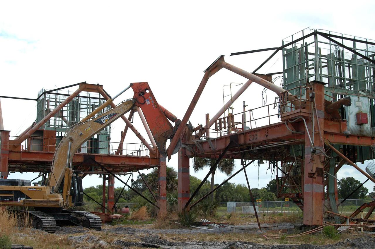 KENNEDY SPACE CENTER, FLA. -- - Launch Umbilical Tower No. 1 (LUT-1) stored in the Industrial Area of KSC is being demolished with a Caterpillar excavator and 48-inch shear attachment.  Seen is the base of tower; the upright tower extended more than 398 feet above the launch pad.  The LUT-1 was part of the launch system used for Apollo-Saturn V, launching Apollo 8, Apollo 11, Skylab manned missions and the Apollo-Soyuz Test Project.  The shear is one used in the deconstruction of the Twin Towers in New York City after 9/11.